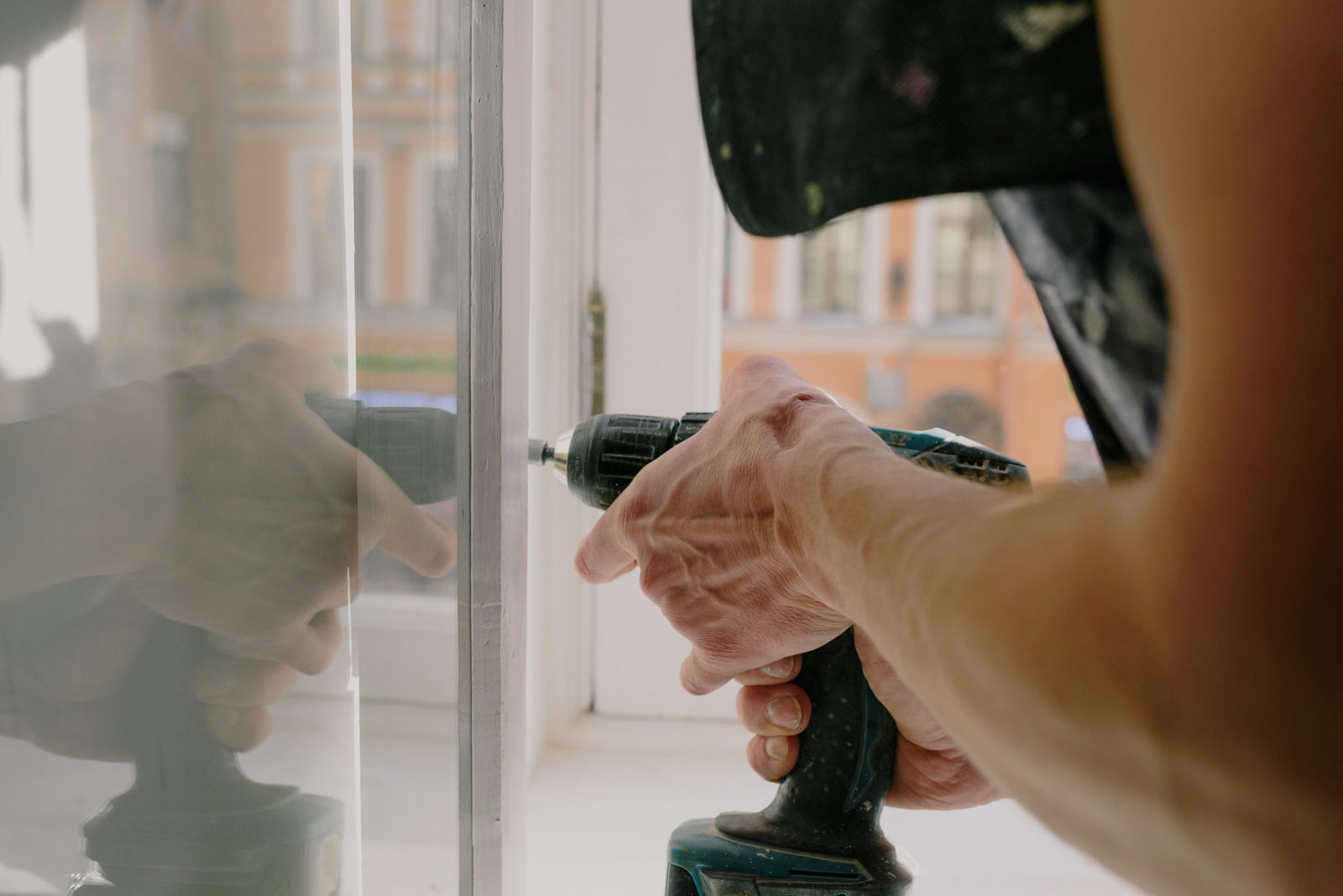 An installer setting a white vinyl window into a wall opening